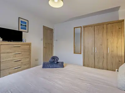 a bedroom with a large bed with a television and cabinets at 2 Bed in Keswick 86001 in Keswick