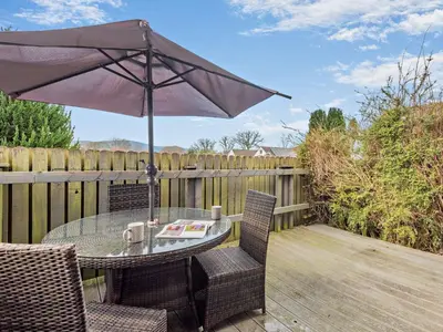a table and chairs with an umbrella on a deck at 2 Bed in Keswick 86001 in Keswick