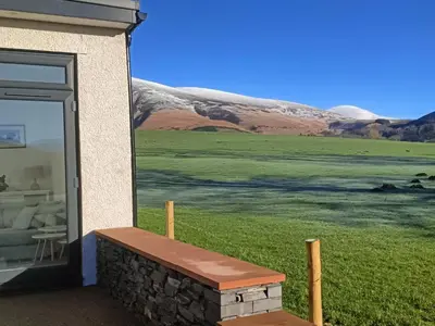 a bench outside of a building with a view of a field at Langrigg Cottage HOT TUB HIRE AVAILABLE in Portinscale