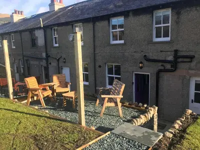 a house with rocking chairs in front of it at 2 Bed in Keswick 88864 in Keswick
