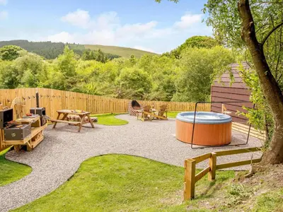 a backyard with a hot tub and picnic tables at 1 Bed in Ennerdale Bridge 88672 in Frizington
