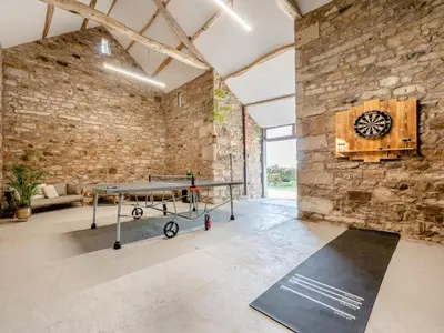 a ping pong table in a room with a stone wall at 5 Bed in Wigton oc-89496 in Torpenhow