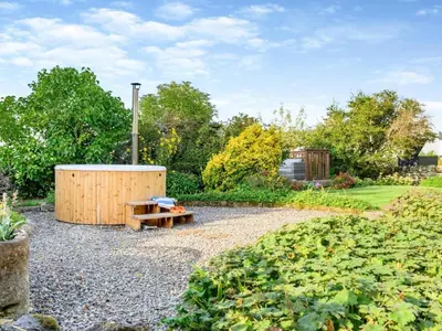 a garden with a wooden bench and a wooden barrel at 5 Bed in Wigton oc-89496 in Torpenhow