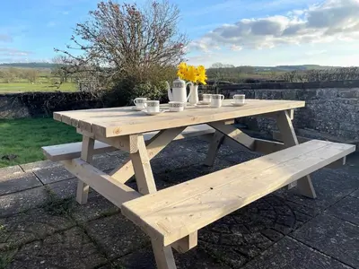 a wooden picnic table with cups and flowers on it at 3 Bed in Aspatria 89139 in Aspatria