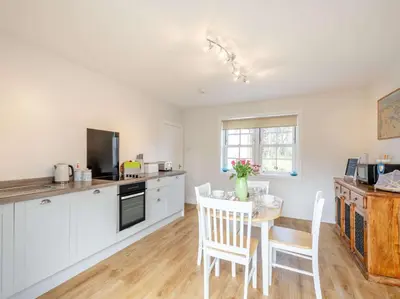 a kitchen with white cabinets and a table with chairs at 2 Bed in Ayr 90039 in Ayr