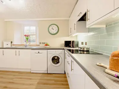 a kitchen with a washing machine and a clock on the wall at 3 Bed in Egremont oc-90050 in Hale