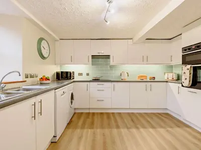 a kitchen with white cabinets and a clock on the wall at 3 Bed in Egremont oc-90050 in Hale