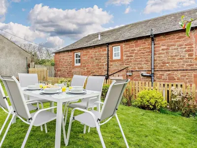 a white table and chairs in the garden of a cottage at 3 Bed in Egremont oc-90050 in Hale