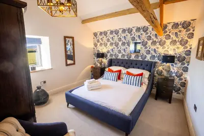 a bedroom with a blue bed with orange pillows at Sheepfold Barn in Penruddock