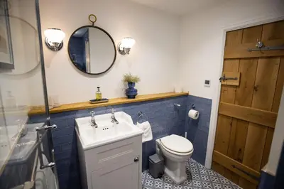 a bathroom with a sink and a toilet and a mirror at Sheepfold Barn in Penruddock