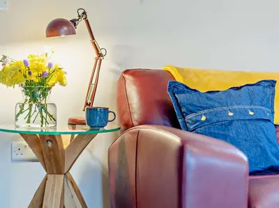 a table with a vase of flowers and a lamp at 2 Bed in Dearham 91132 in Dearham