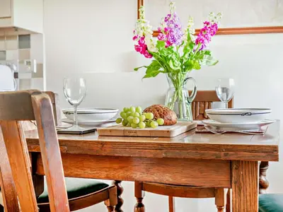 a dining room table with a vase of flowers at 1 Bed in Mosedale 91232 in Mosedale