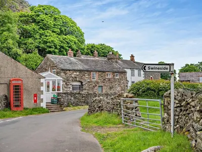 a street sign in front of a stone house at 1 Bed in Mosedale 91232 in Mosedale