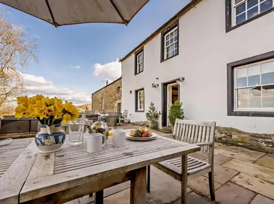 a wooden table with a vase of flowers on a patio at 5 Bed in Cockermouth oc-91503 in Embleton