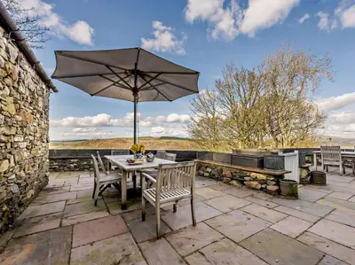 a table and chairs with an umbrella on a patio at 5 Bed in Cockermouth oc-91503 in Embleton