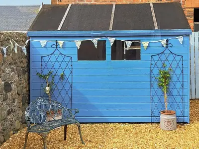 a blue shed with a chair in front of it at Corner Cottage in Girvan