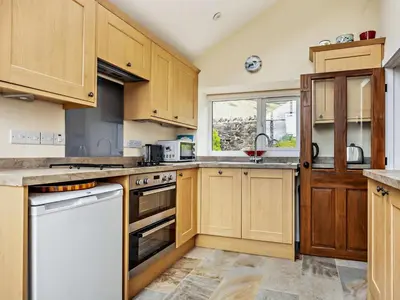 a large kitchen with wooden cabinets and a window at 1 Bed in Penrith oc-91812 in Dockray