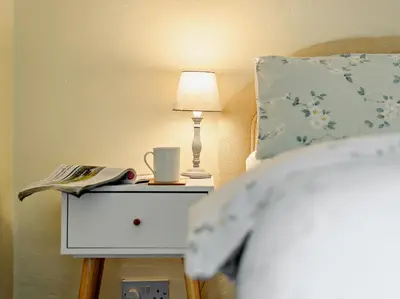 a bed with a nightstand with a lamp and a book at 1 Bed in Gilcrux 92218 in Gilcrux
