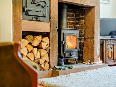 a wood stove with a pile of fire wood at 1 Bed in Gilcrux 92218 in Gilcrux
