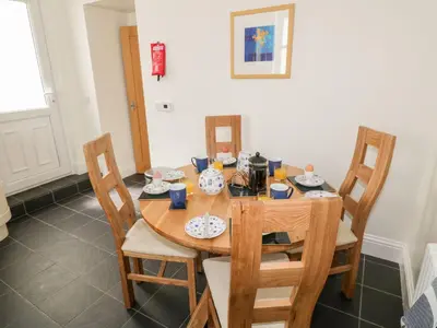 a dining room table with four chairs and a wooden table at Haven Cottage in Kirkcudbright