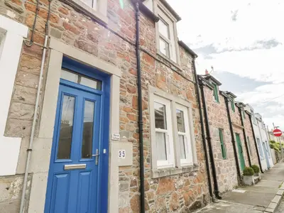a brick building with a blue door on a street at Haven Cottage in Kirkcudbright