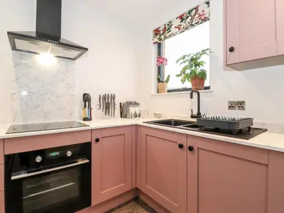 a kitchen with red cabinets and a sink and a window at Herdwick Cabin in Penrith