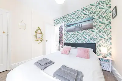 a bedroom with a large white bed with pink pillows at Charming Cottage, Lake District in Little Broughton
