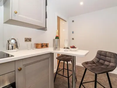 a kitchen with a counter and two stools at The Gardener's Retreat in Penrith