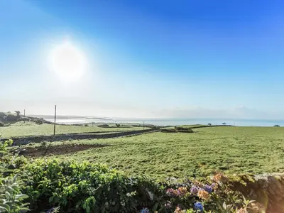 a field with the ocean in the background at High Auchenlarie Cottage in Carsluith