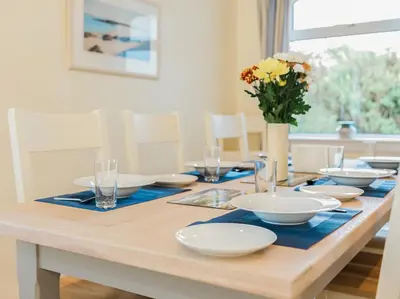 a dining room table with white dishes and a vase of flowers at High Auchenlarie Cottage in Carsluith