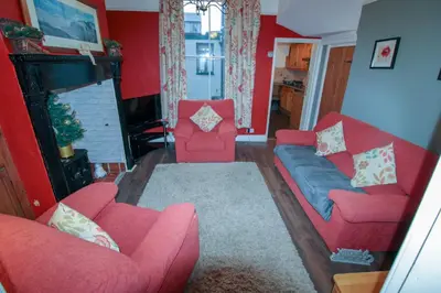 a living room with two red couches and a fireplace at Carlton Cottage all ground floor, centrally located in Keswick in Keswick