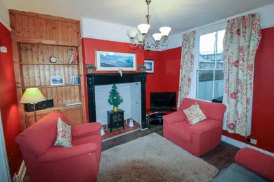 a living room with two red chairs and a fireplace at Carlton Cottage all ground floor, centrally located in Keswick in Keswick