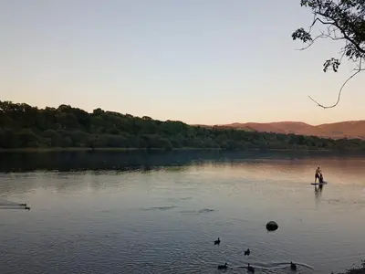 a man on a paddle board in a lake with ducks at Emilys Nook Ireby, budget accommodation with fell views in Ireby