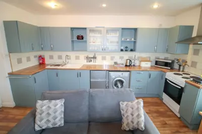 a kitchen with blue cabinets and a couch in it at Emilys Nook Ireby, budget accommodation with fell views in Ireby