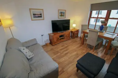 a living room with a couch and a table and a television at Glenmore, Hewetson Court, centrally located 1st floor apartment in Keswick in Keswick