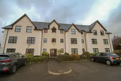 a large house with cars parked in a parking lot at Glenmore, Hewetson Court, centrally located 1st floor apartment in Keswick in Keswick
