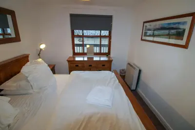 a bedroom with a large white bed and a window at Glenmore, Hewetson Court, centrally located 1st floor apartment in Keswick in Keswick