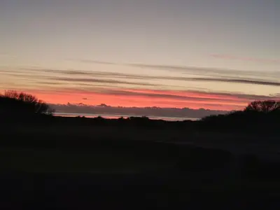 a sunset over a field with trees in the foreground at Birds Eye View in Mainsriddle