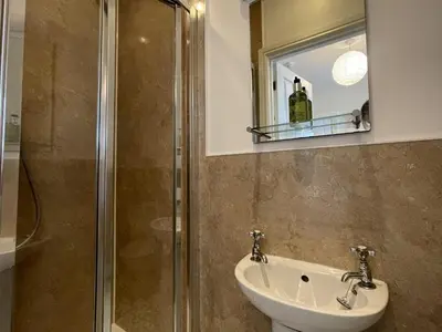 a bathroom with a shower and a sink and a mirror at Ellergill in Keswick