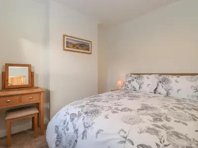 a bedroom with a bed and a table with a mirror at Jack's Cottage in Keswick