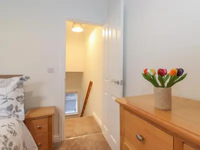 a bedroom with a dresser with a vase of tulips on it at Jack's Cottage in Keswick