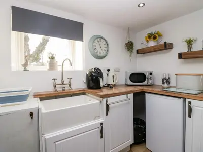 a kitchen with a sink and a clock on the wall at High Wreah Bolt Hole in Whitehaven