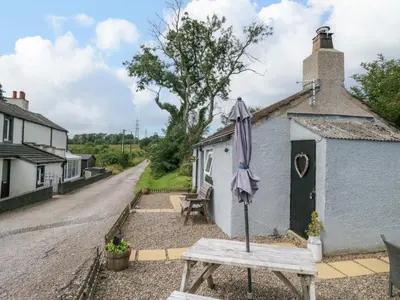 an umbrella sitting on a table in front of a house at High Wreah Bolt Hole in Whitehaven