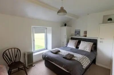 a bedroom with a large bed and a window at Escape to our Cosy Cottage with Log Burner in Drigg, Lake District in Drigg