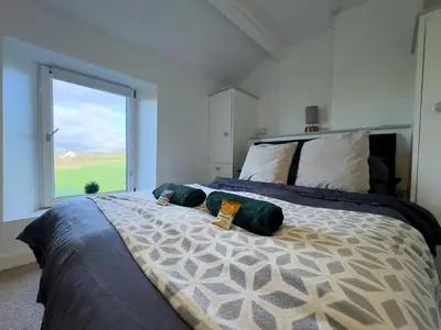 a bedroom with a large bed with a large window at Escape to our Cosy Cottage with Log Burner in Drigg, Lake District in Drigg