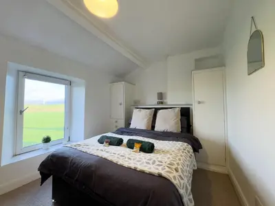 a bedroom with a large bed with a window at Escape to our Cosy Cottage with Log Burner in Drigg, Lake District in Drigg