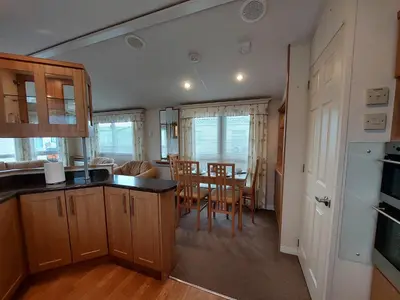 a kitchen and dining room with a table and chairs at Winnie - Caravan mit Meerblick in Drummore