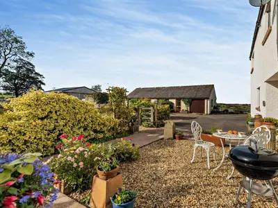 a garden with a table and chairs and flowers at 2 Bed in Bassenthwaite 93463 in Ireby