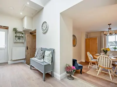 a living room with a table and a clock on a wall at 2 Bed in Bridekirk 93280 in Bridekirk