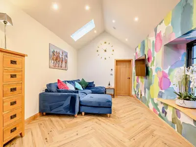 a living room with a blue couch and a clock on the wall at 1 Bed in Lockerbie 93110 in Lockerbie